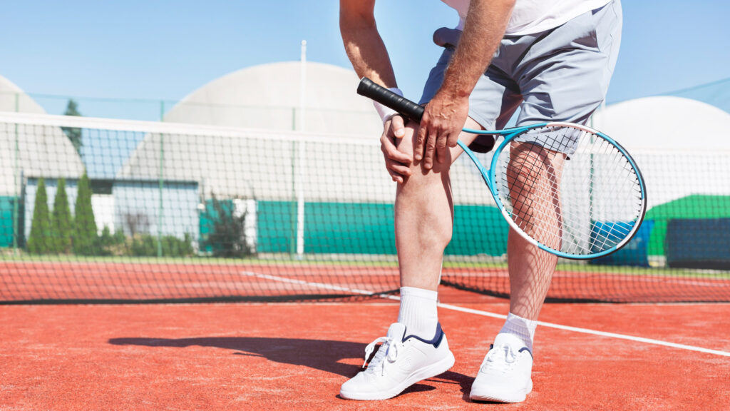 Chiropractic Care in Tennis - A tennis player grabbing his knee in pain 
